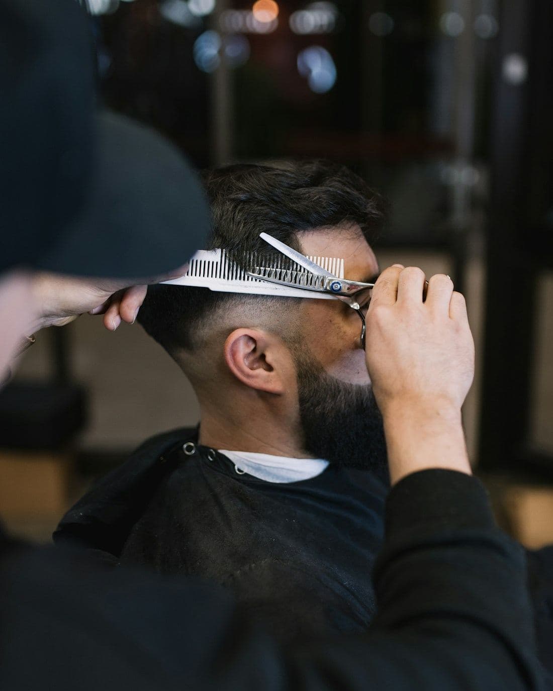 A barber cutting with scissors over comb