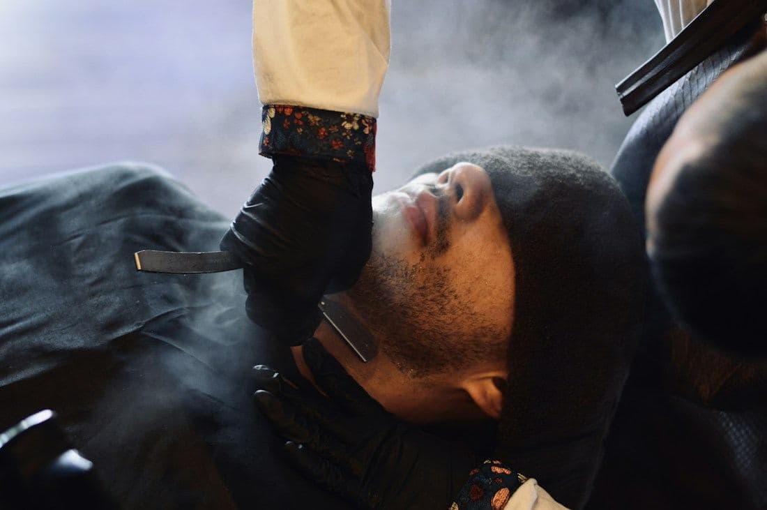 A hot-towel straight-razor shave in progress, steam rising